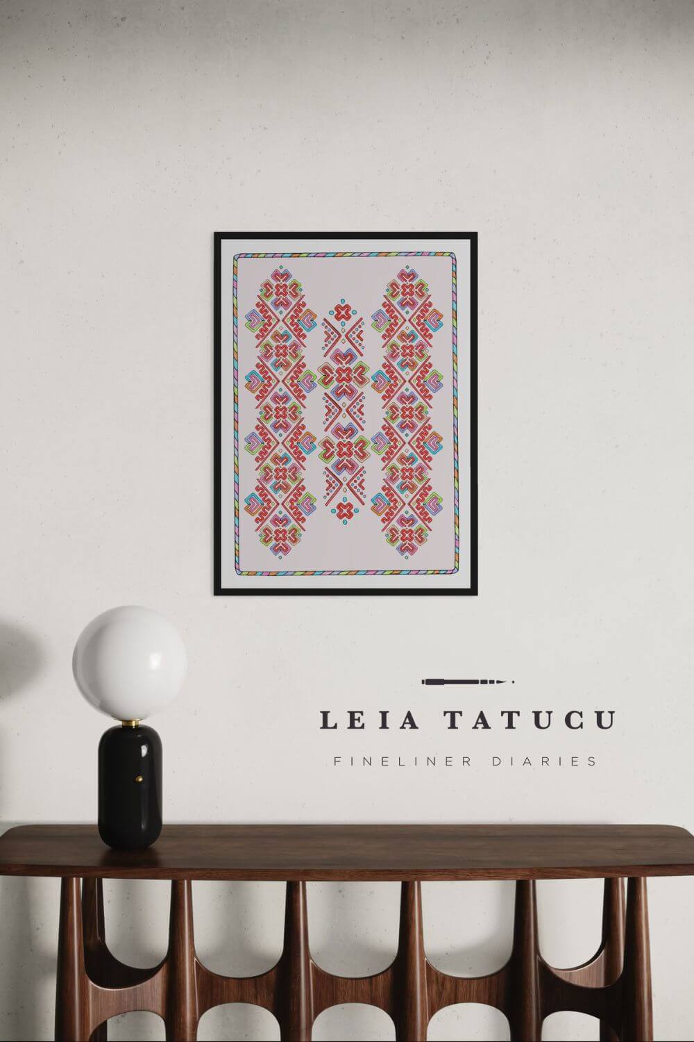 Geometric motif pattern artwork from Romanian traditional headpiece, framed print on a wooden table with lamp.